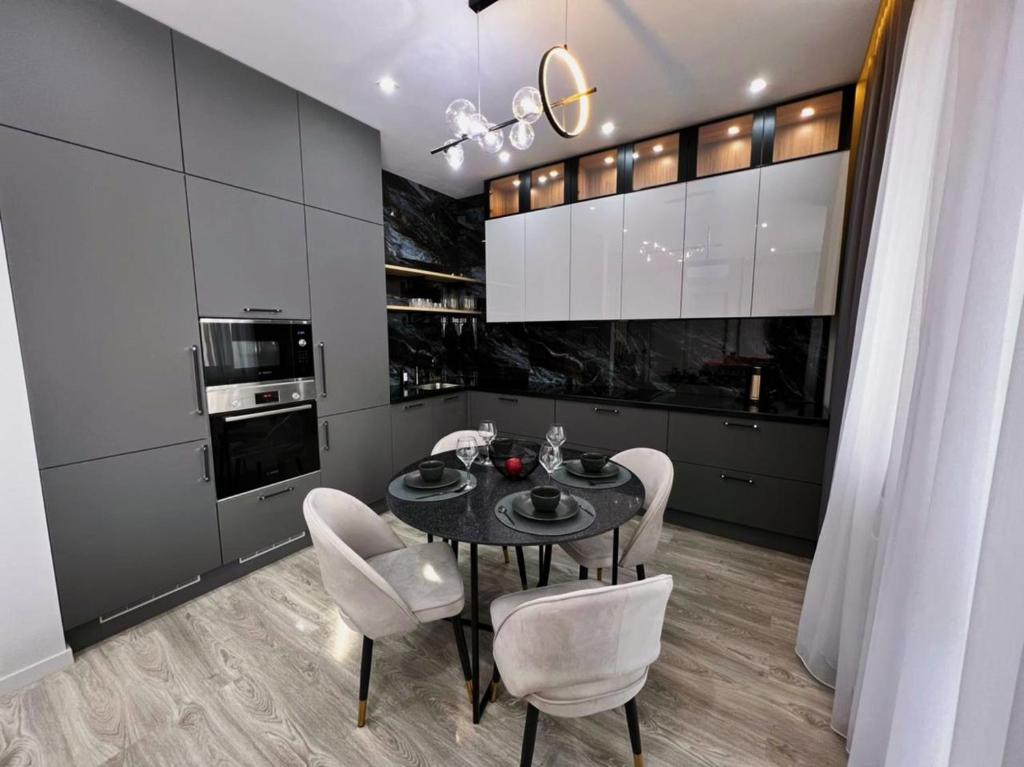 una cucina con tavolo nero e sedie bianche di Royal Lux апартаменты в ЖК ZAMAN a Atyraū