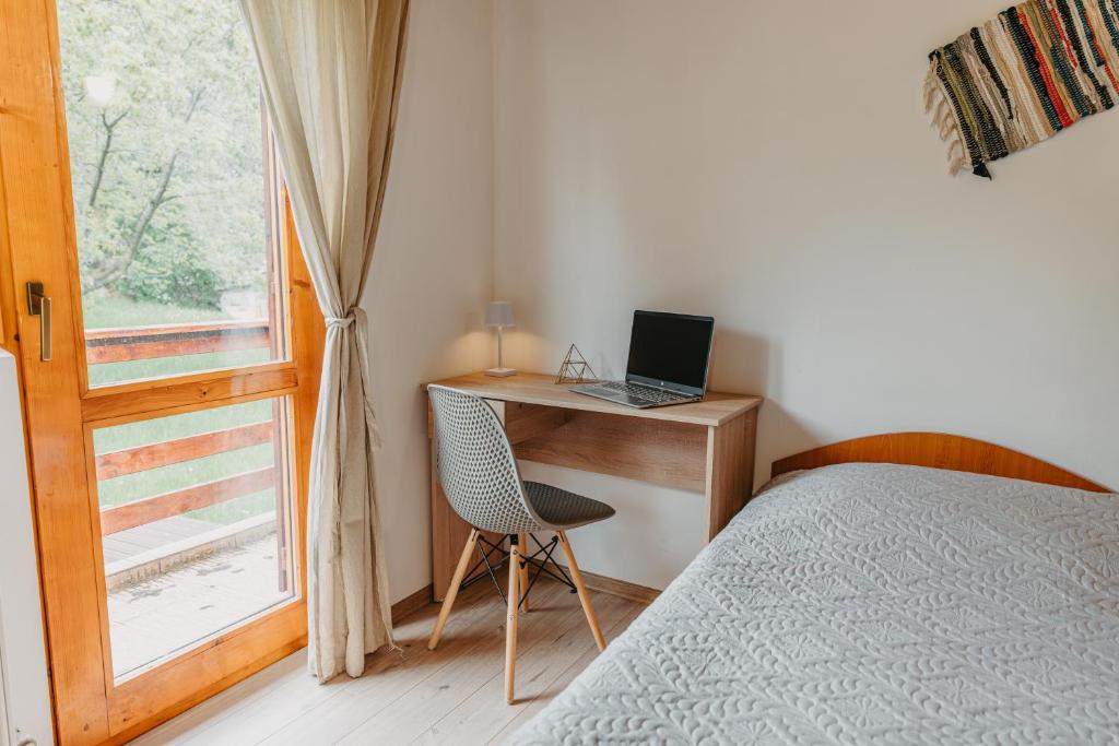 a bedroom with a bed and a desk with a laptop at Villa Forrest Bușteni in Buşteni