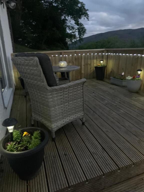 a wicker chair and a table on a deck at Alt-an Retreat Lodge overlooking loch linnhe in Fort William