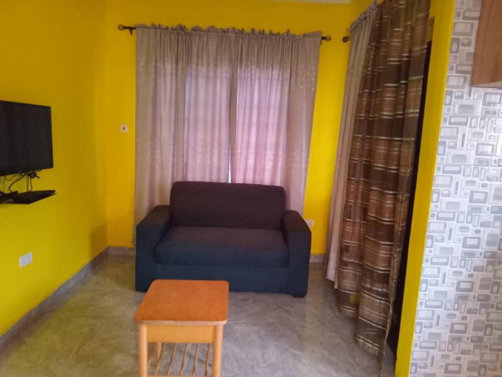 uma sala de estar com um sofá azul e uma mesa em Abokobi Cosy Home em Accra