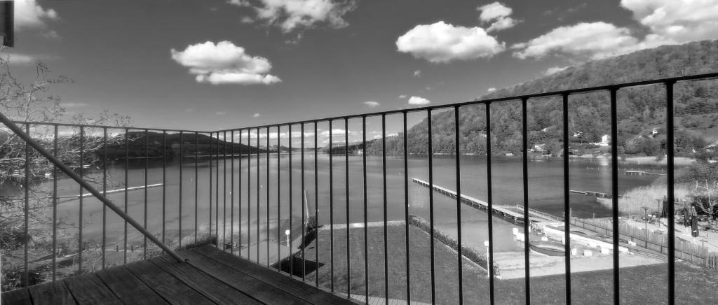 ein schwarz-weißes Foto eines Zauns neben einem Wasserkörper in der Unterkunft Beau Rivage in Charavines