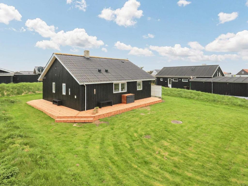 una casa negra en un campo con un patio en Three-Bedroom Holiday home in Løkken 38, en Løkken