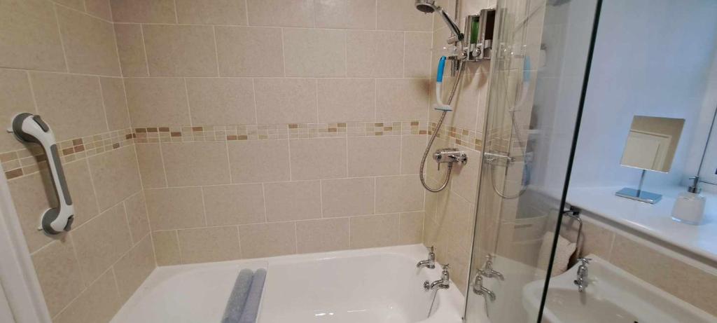 a bathroom with a shower and a tub and a sink at Cliff Cottage in Valtos