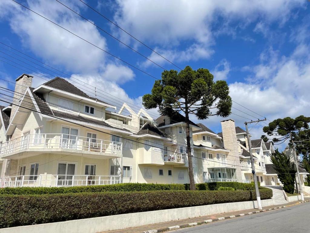 un edificio blanco con un árbol delante en Cobertura em Campos do Jordão-Capivari, en Campos do Jordão