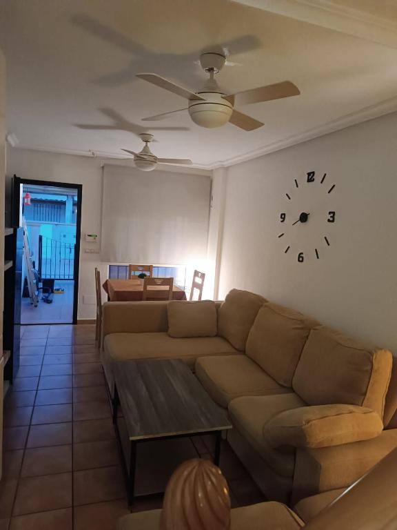 a living room with a couch and a clock on the wall at Adosado mediterráneo in Orihuela Costa