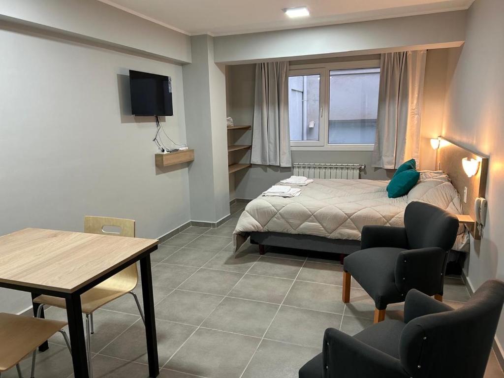 Un dormitorio con una cama y una mesa y sillas. en Monoambiente M670, en San Carlos de Bariloche