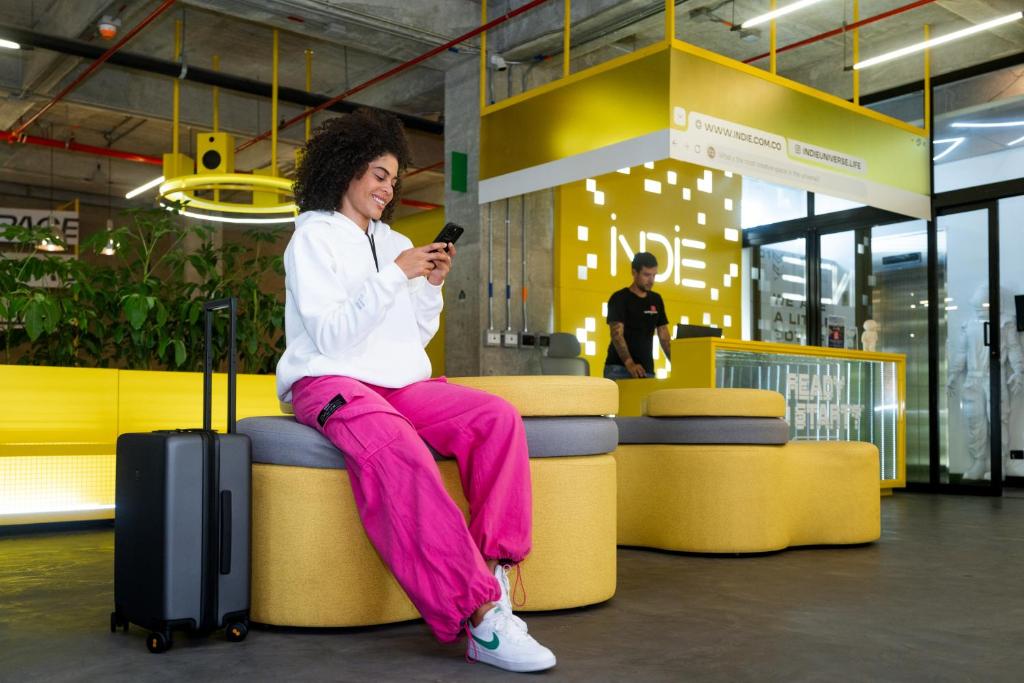 una mujer sentada en un banco mirando su celular en Indie Universe Creative Hotel en Medellín