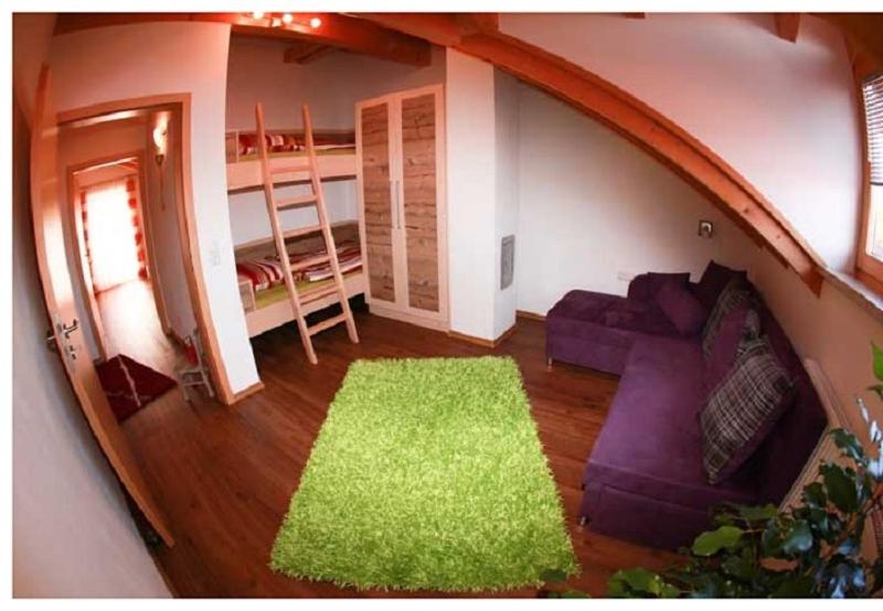 sala de estar con sofá púrpura y alfombra verde en Ferienwohnung Mühl, en Zwiesel