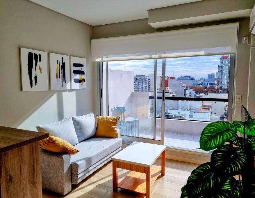ein Wohnzimmer mit Couch und großem Fenster in der Unterkunft Rooftop Sunlight Movistar Arena in Buenos Aires