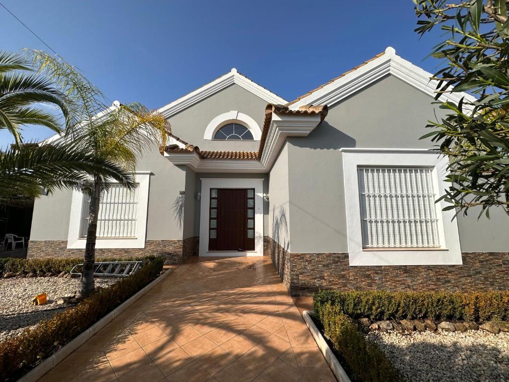 a house with a palm tree in front of it at Chalet Californiano con Piscina in Morón de la Frontera
