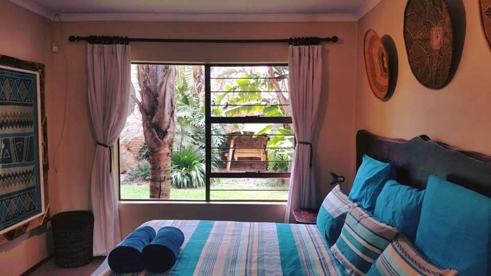 a bedroom with a bed and a large window at UrbanEscape in Centurion