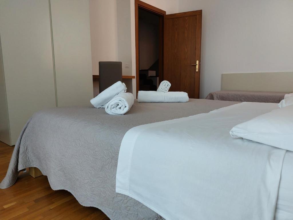 1 dormitorio con 2 camas, sábanas blancas y toallas en Le Betulle Affittacamere, en Sona