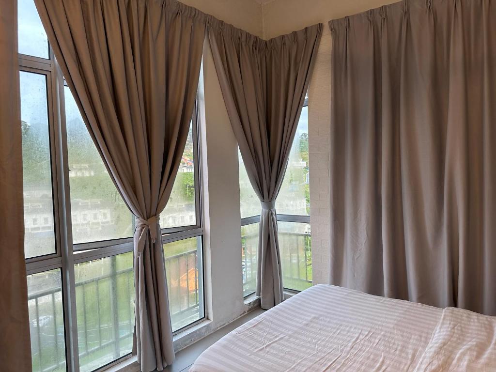 a bedroom with a bed and two windows with curtains at A5 Barrington Square 1 Room Apartment in Cameron Highlands