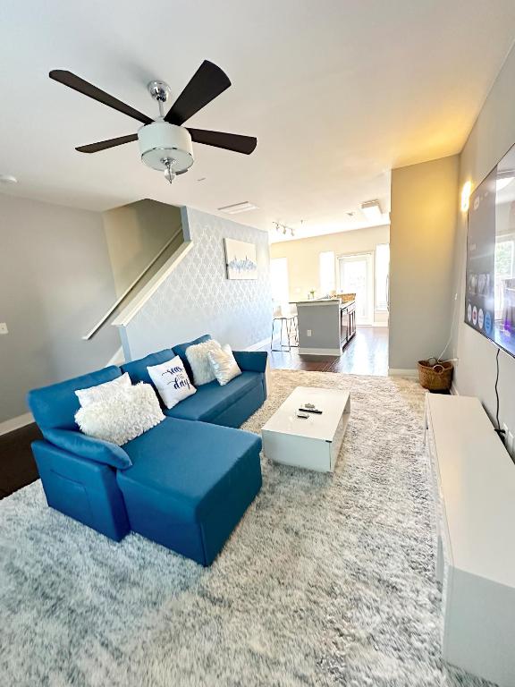 a living room with a blue couch and a ceiling fan at Uptown CLT - Modern Townhouse in Charlotte