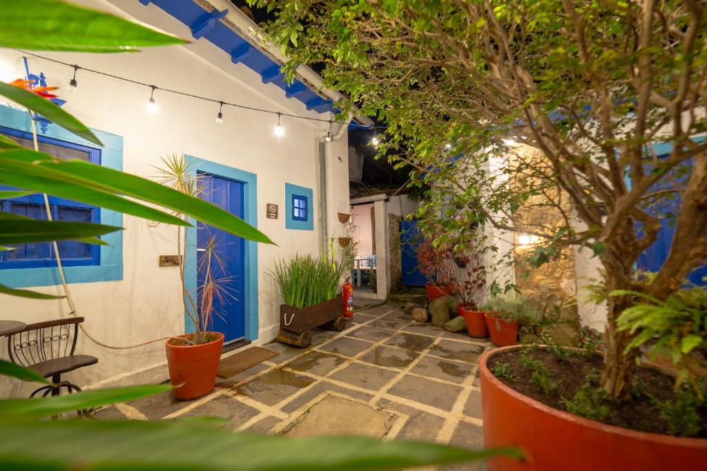 une cour avec des plantes en pot et une porte bleue dans l'établissement Casas do Pátio Pousada & Bar, à Parati