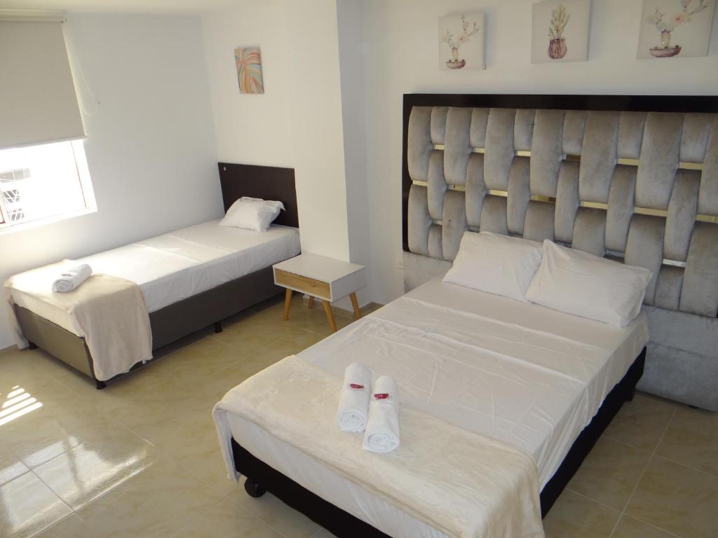 um quarto de hotel com duas camas com chinelos na cama em San Alejo em Tuluá