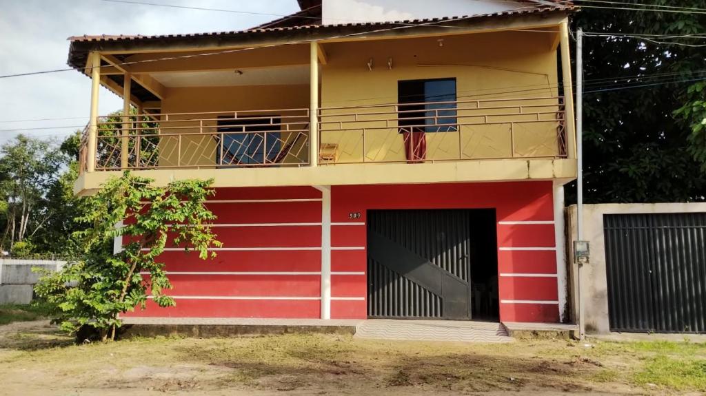 Maison rouge et blanche avec balcon dans l'établissement Pousada Sossego de Alter, à Alter do Chão