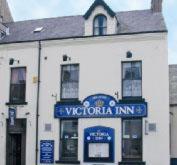 a white building with a blue sign for a victoria inn at Victoria Inn in Alston