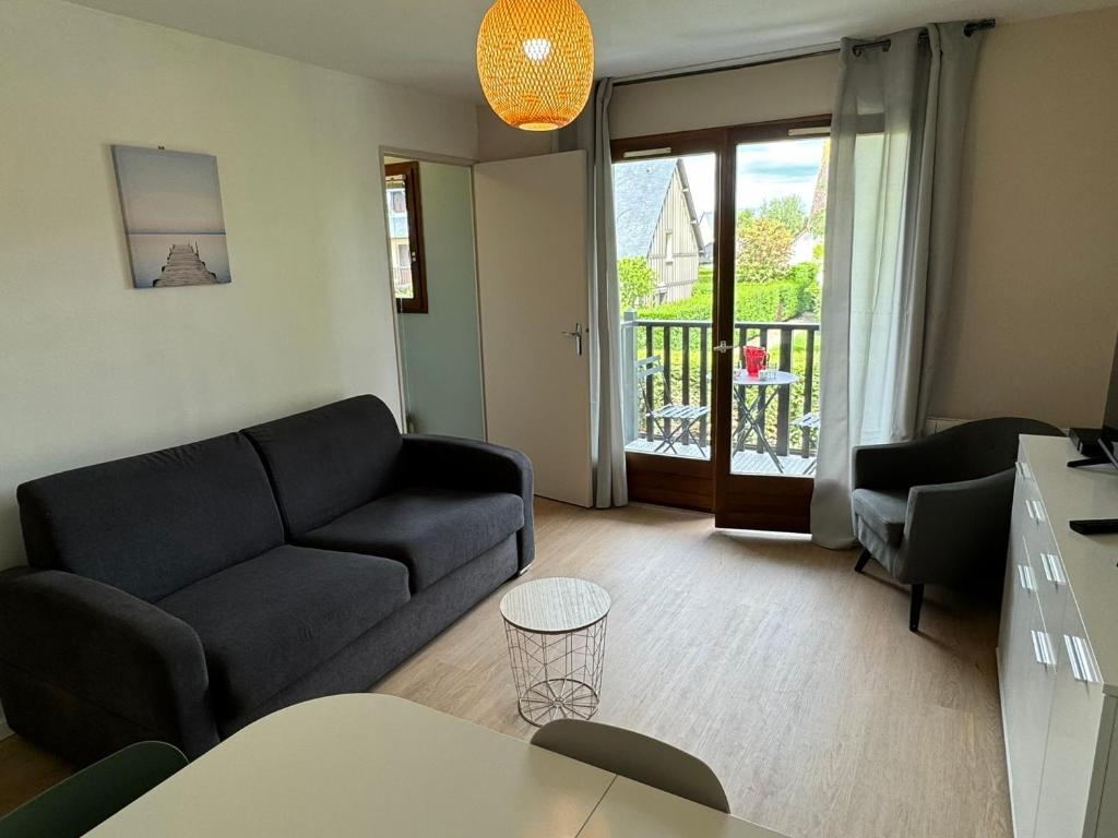 un salon avec un canapé et une table dans l'établissement Appartement 2P rénové à Cabourg, proche plage et thalasso, avec balcon et parking, 4 pers. - FR-1-487-368, à Cabourg