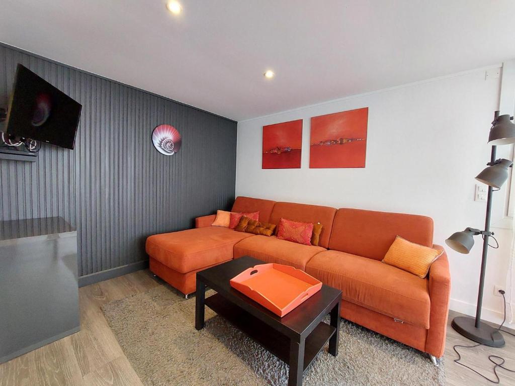 - un salon avec un canapé orange et une télévision dans l'établissement Charmant T2 près de la plage à Pontaillac - FR-1-550-77, à Royan