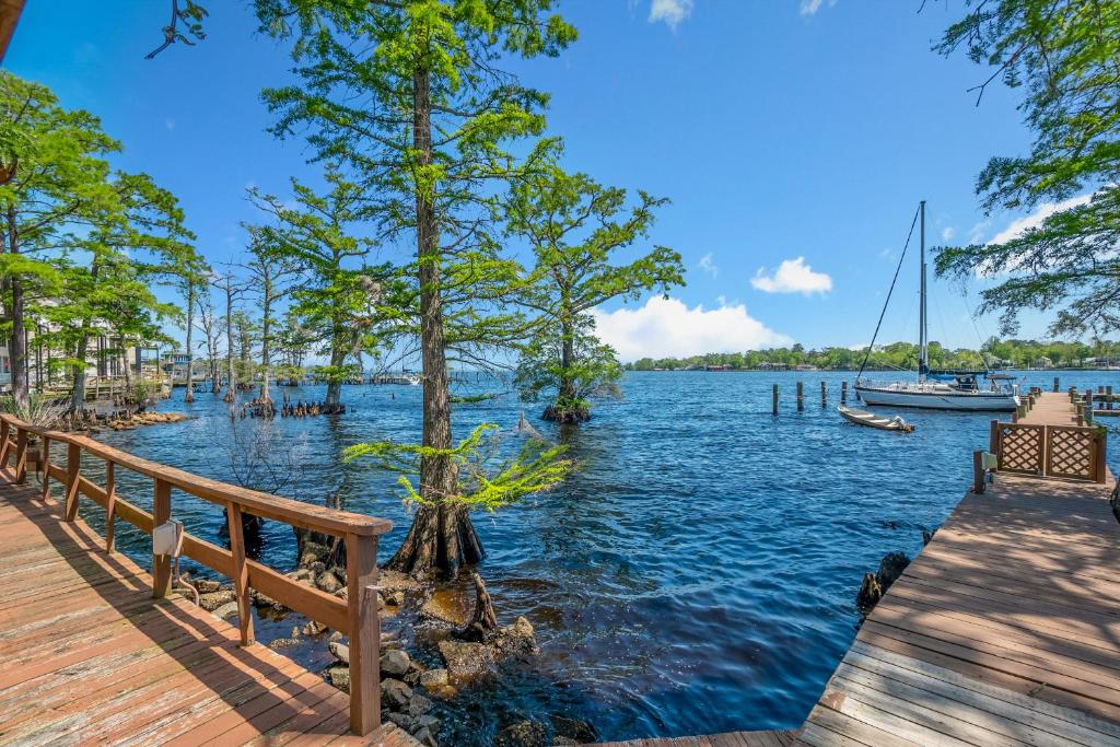 uma doca com uma árvore e um barco na água em Water Front Condo with Boat Slip: The Dock House em Elizabeth City