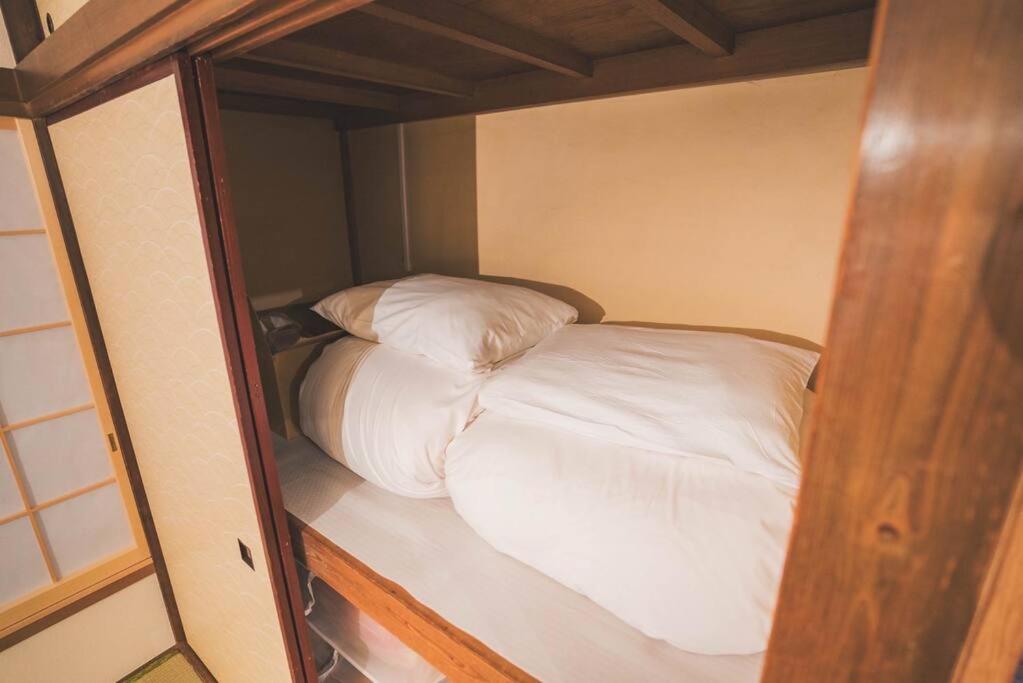 a small bed with white sheets and pillows at New! Kamata close Haneda AP - Traditional & Hot Spring in Tokyo