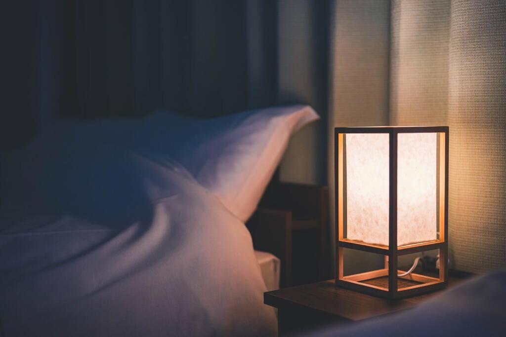 a lamp sitting on a table next to a bed at New! Kamata close Haneda AP - Traditional & Hot Spring in Tokyo