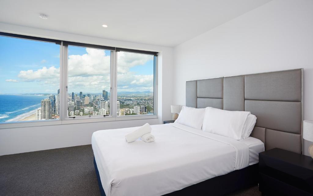 um quarto com uma grande cama branca e janelas grandes em Serain Residences on 9 Hamilton Avenue em Gold Coast