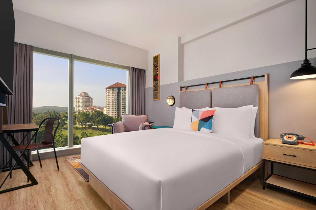 a bedroom with a large white bed and a window at Moxy Putrajaya in Putrajaya