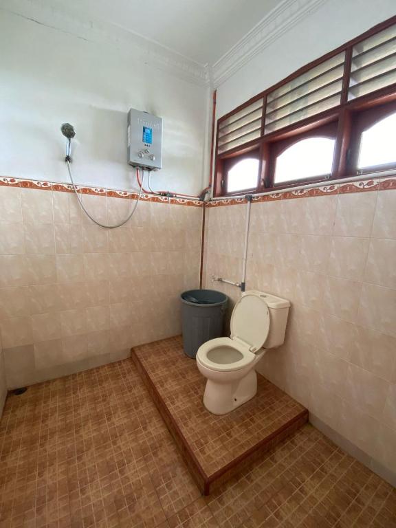 a bathroom with a toilet and a trash can at Sibayak Multinational Rest House in Berastagi