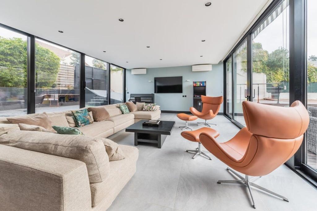 un salon avec un canapé, des chaises et des fenêtres dans l'établissement Maison d'Architecte aux Portes de Paris, à LʼHay-les-Roses