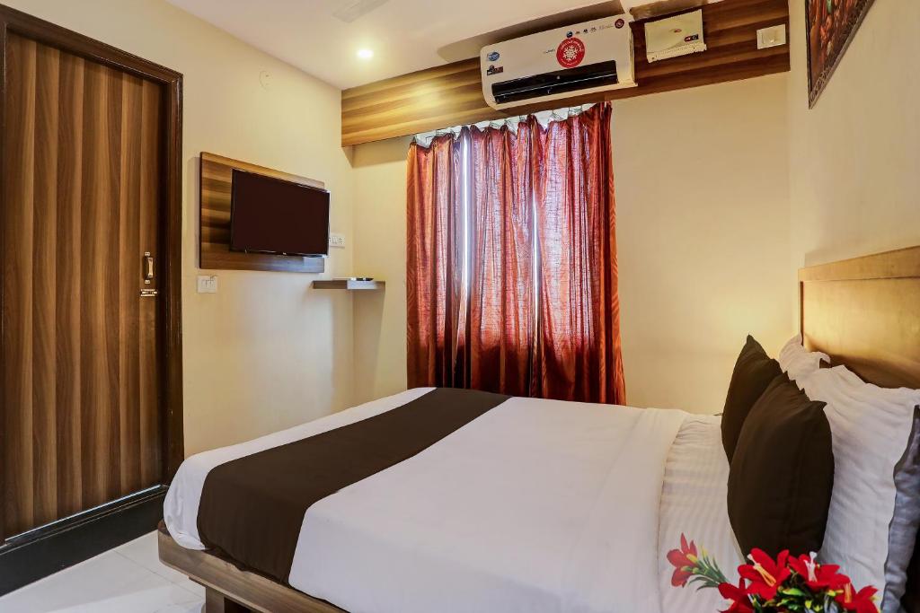 ハイデラバードにあるSuper OYO 16428 Hotel Vaishnavi Innのベッドとテレビが備わるホテルルームです。