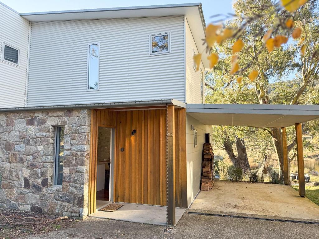a house with a wooden door and a stone wall at Iron Bark Chalet in Crackenback