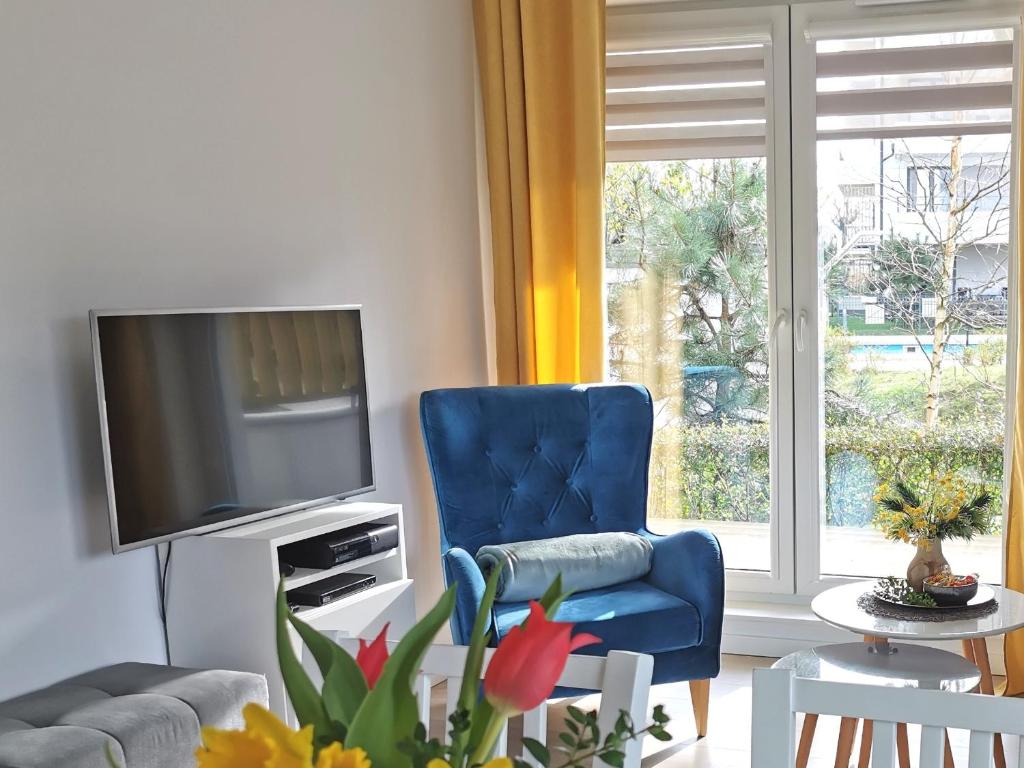 sala de estar con silla azul y TV en Apartamenty Wybrzeże Laguna en Ustronie Morskie