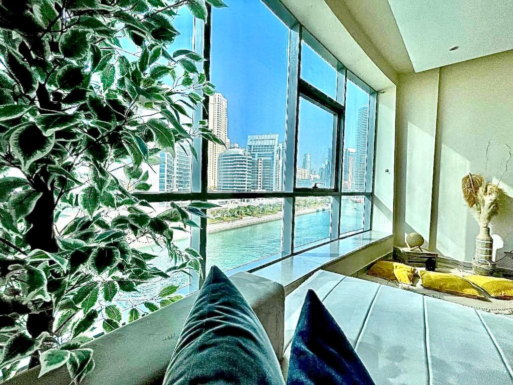 een woonkamer met een groot raam en een grote plant bij Wonderful two bed room with full marina view in Dubai