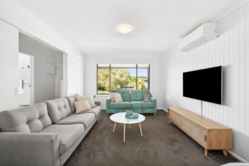 a living room with a couch and a tv at The Absolute Beach Escape For 21 in Saint Leonards