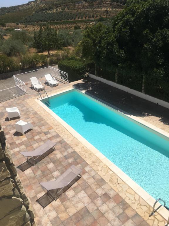 una piscina con due sedie a sdraio di Stria House a Mazzarino