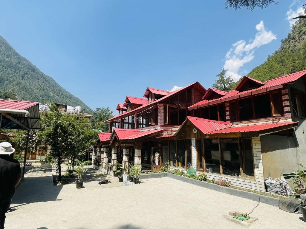 un edificio con techos rojos con montañas al fondo en The Lalits Kitchen, en Kasol