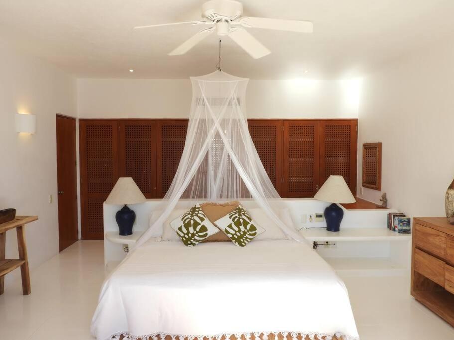 a bedroom with a white bed with a ceiling fan at Casita Canario - Ocean views & Careyes luxury! in Careyes
