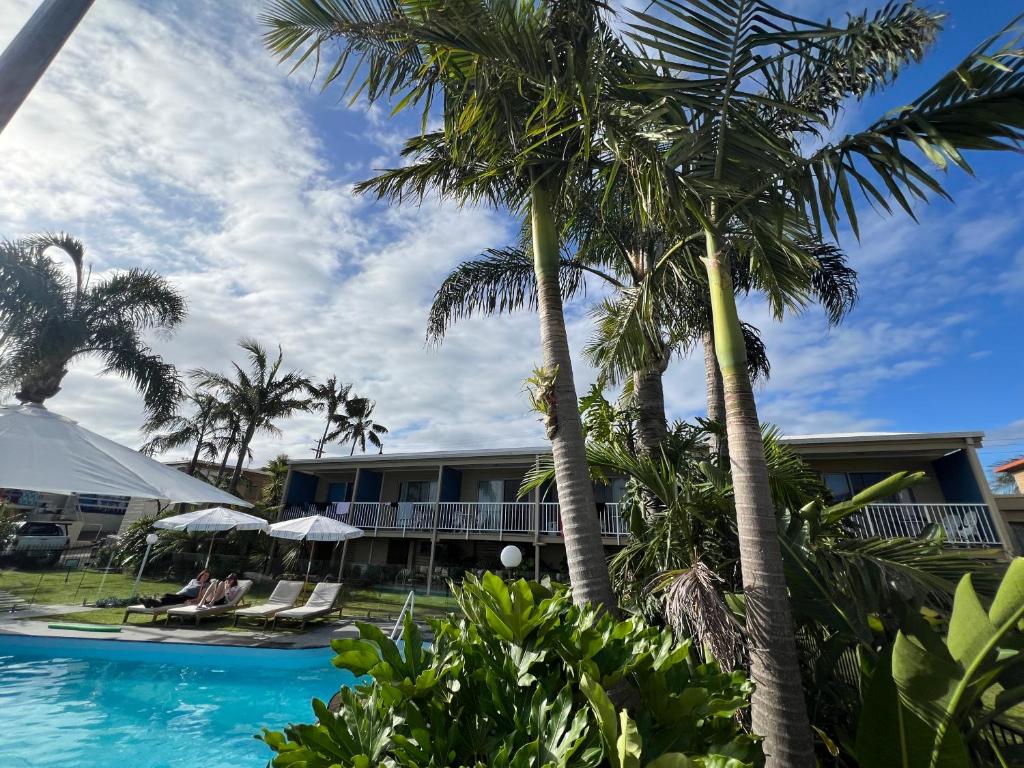 un complejo con palmeras y piscina en South Seas Motel, en Merimbula