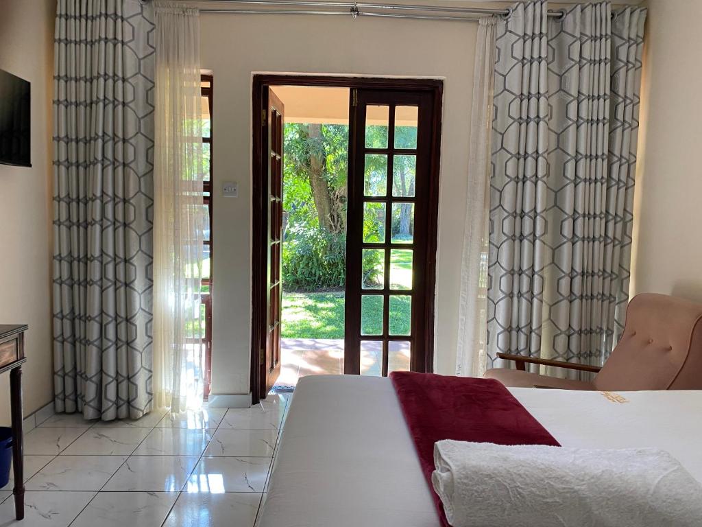 um quarto com uma cama e uma porta de vidro deslizante em Matilinda Lodge em Bulawayo