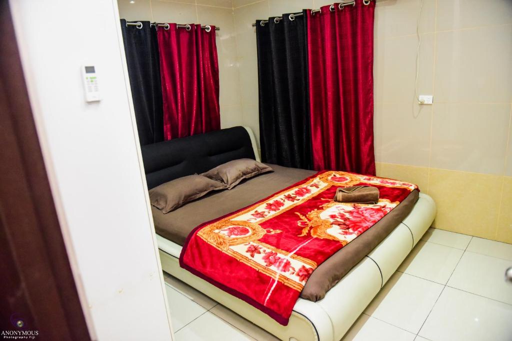 ein kleines Zimmer mit einem Bett mit roten Vorhängen in der Unterkunft Shashi's Villa & Luxurious Apartments in Lautoka