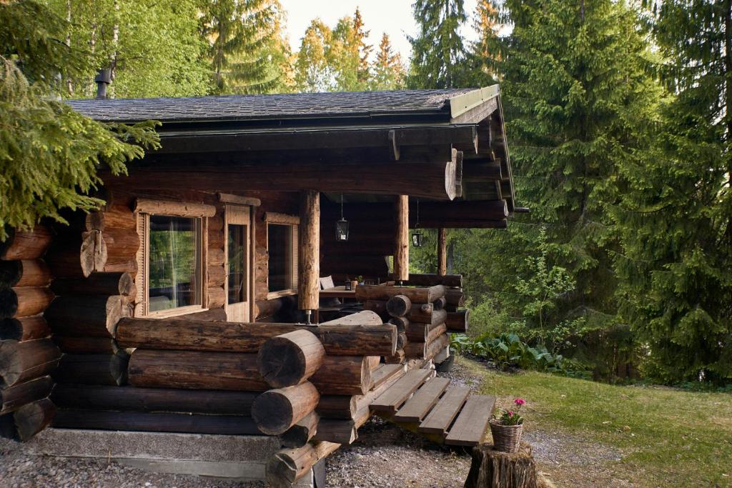 una cabaña de madera con un banco delante en Hawkhill cottage resort, en Tervalampi