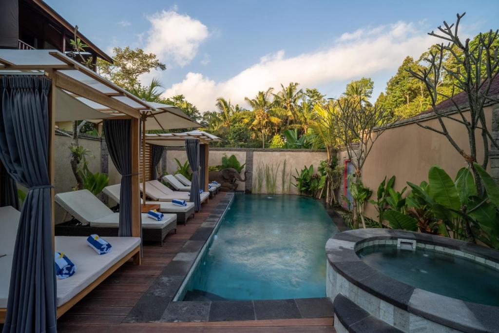 una piscina con tumbonas y una piscina en The Compass Rose Ubud en Ubud