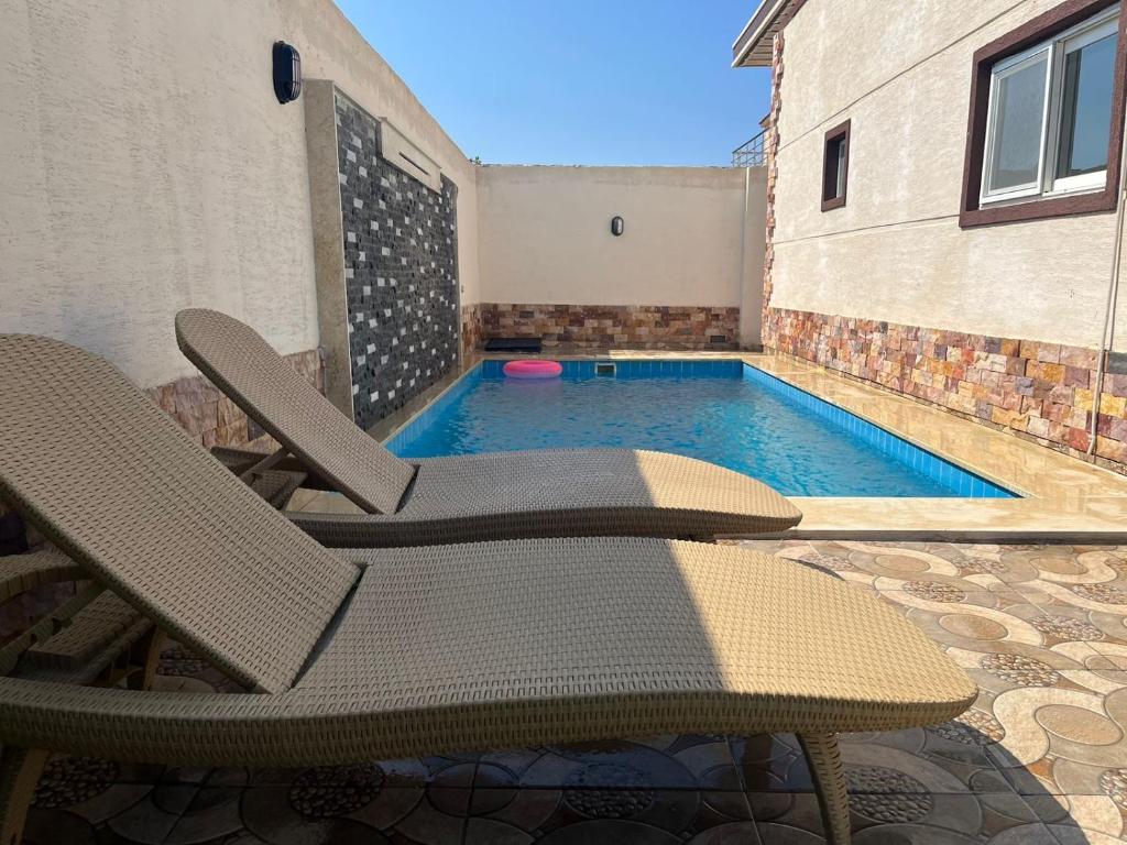 eine Terrasse mit 2 Stühlen und einem Pool in der Unterkunft Nubian Villa with Private Pool in Naj‘ al Aḩwāl