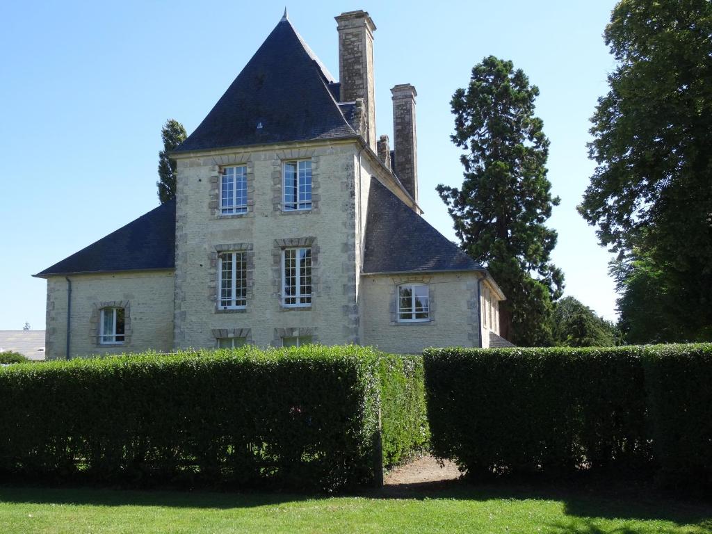 ein altes Haus mit Kamin und ein paar Büschen in der Unterkunft Château Turgot Gîtes in Bons-Tassily