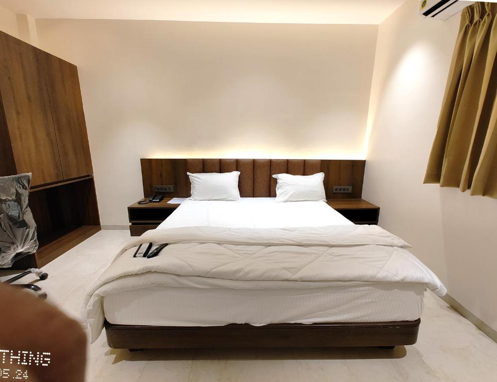 1 dormitorio con 1 cama grande con sábanas y almohadas blancas en HOTEL 3T WORLD, en Nanded