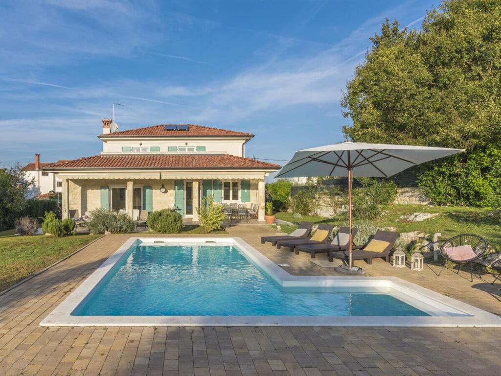 una piscina frente a una casa con sombrilla en Villa Lara Rovinj, en Rovinjsko Selo