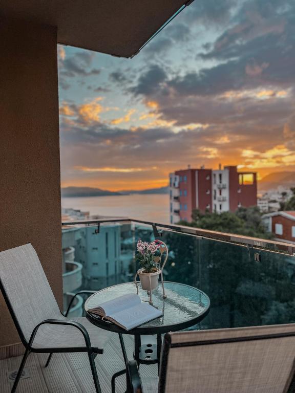a balcony with a table and chairs and a sunset at Vanja Apartment with Private Parking - Sea View in Pržno
