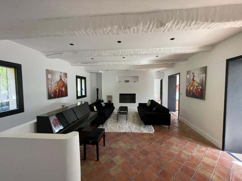 un soggiorno con divani neri e TV di Villa provençale, 8 personnes, très grande piscine et jardin, au calme, salle de fitness et espace coworking a Opio